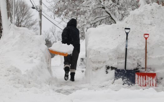 image of a person digging their sidewalk clear of 5 feet of snow